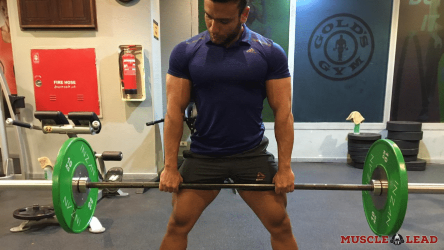 A male lifter performing the top part of a deadlift